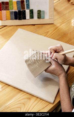 Close up female hands make dishes from clay. Woman potter in apron making pottery in studio Stock Photo
