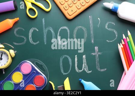 Phrase School's Out and school supplies on chalkboard, flat lay Stock Photo