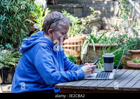 A female professional working from home, in the garden, London, UK Stock Photo