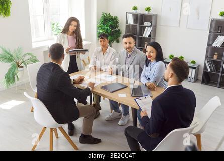 Company employees working on their workplace in office discussing job and work projects. Stock Photo