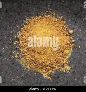 Pile of granulated coconut blossom sugar close up on black ceramic plate Stock Photo