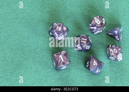 Gray polyhedral dices for Dungeons and Dragons board game playing on green baize table with copyspace Stock Photo
