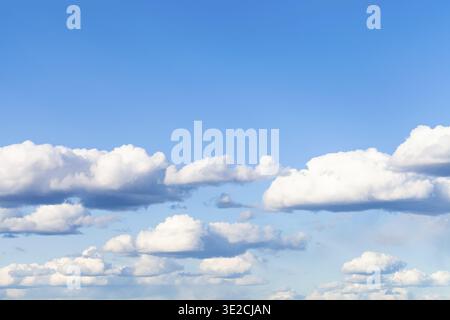 Many low small cumulus clouds in blue sky on March day Stock Photo