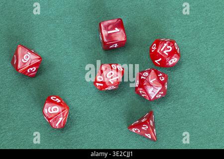 Set of red polyhedral dices for Dungeons and Dragons board game playing on green baize table Stock Photo