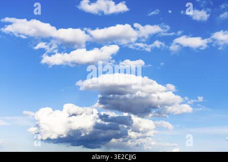 Few low dark rainy clouds and many little white clouds in blue sky on March day Stock Photo
