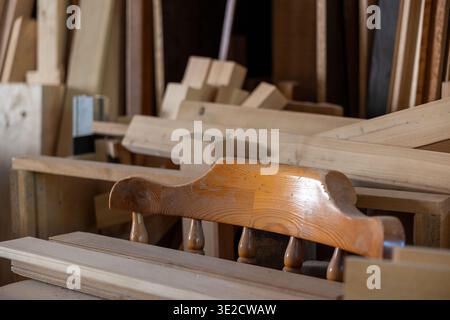 Various cuts of timber, planks, and raw wood materials are neatly stacked and stored in a dusty carpentry workshop, ready for craftsman projects and j Stock Photo