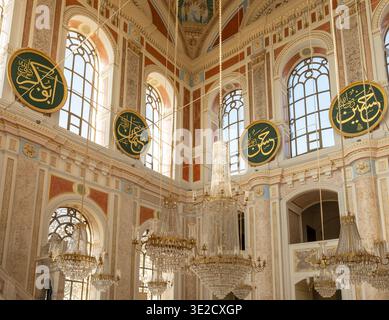 Luxurious mosque interior with soaring arches crystal chandeliers marble details and large Arabic calligraphy medallions lit by soft daylight Stock Photo