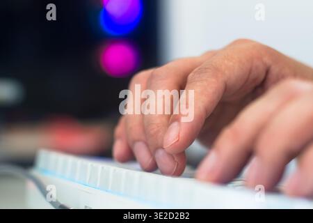 Close up of hands typing on white mechanical keyboard with copy space and blurred background for productivity and gaming concept Stock Photo