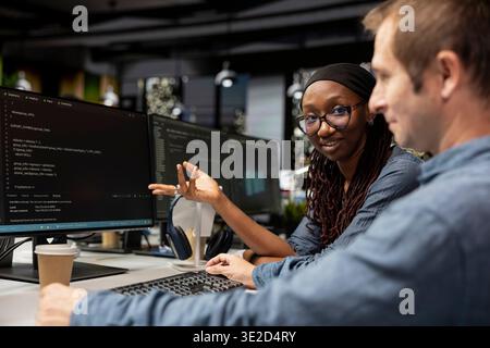 Smiling engineer and coworker cooperating in AI focused startup, designing, coding and debugging applications. Cheerful IT experts doing brainstorming, testing code, doing quality assurance Stock Photo