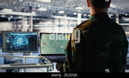 Army specialist in data center integrating AI into radar systems for missile tracking. Military soldier in server room analyzing aerial movement through artificial intelligence systems, camera B Stock Photo