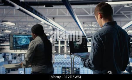 Software developer in data center checks AI dashboard using laptop during routine systems review. Server hub IT specialist tests artificial intelligence on notebook to check performance, camera A Stock Photo