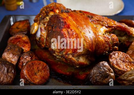 Roasted whole pork leg served in baking dish with potatoes Stock Photo