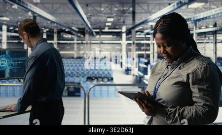 Teamworking data center programmers investigate neural networks configuration, making adjustments for optimal function. Server hub colleagues work together to check deep learning errors, camera A Stock Photo