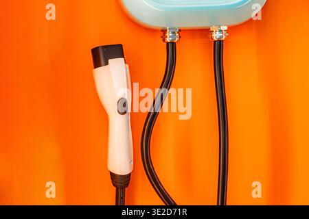 Close-up view of an electric shaver on light orange background, connected to power cord Additional cords and plugs visible nearby Angled perspective, Stock Photo