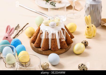 Easter cake with painted eggs and bunnies on table setting for Easter celebration. Closeup Stock Photo