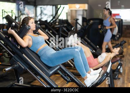Woman doing squats in a machine Stock Photo