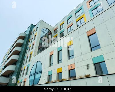 A building features a mix of colors on its exterior. Windows are arranged in different patterns. The sky is gray, indicating it is likely overcast. Stock Photo