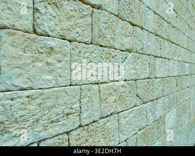 A close view of a stone wall with light colors and varied textures. The scene shows neat stacking and different shapes of stones in natural daylight. Stock Photo