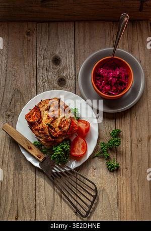 A rustic, top-down photograph of a beautifully baked tomato and onion focaccia bread, served on a white plate with a side of a red cabbage salad. Stock Photo