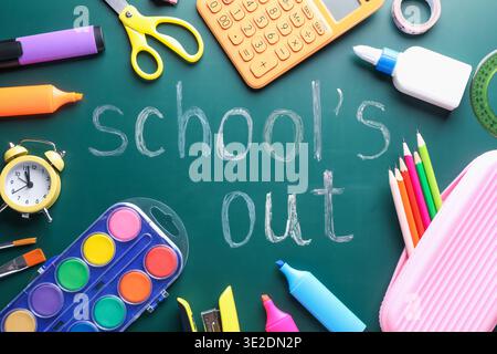 Phrase School's Out and school supplies on chalkboard, flat lay Stock Photo