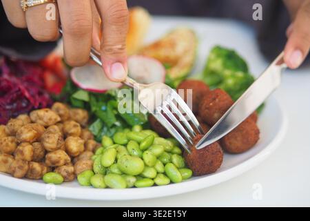 Cutting food on a plate with vegetables and falafel balls Stock Photo