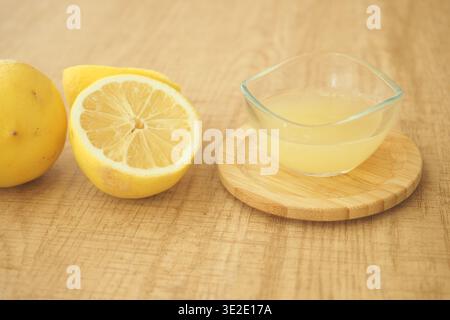 Lemons cut and juice in a bowl on wooden surface Stock Photo