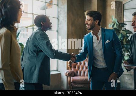 A diverse business team celebrates a successful onboarding moment with a professional handshake during a leadership meeting in a modern office environ Stock Photo