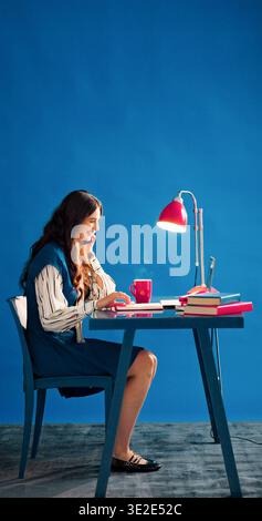 Laptop, phone call and smile with designer woman in studio for agenda, planning or schedule. Computer, journal and space with happy employee on blue Stock Photo
