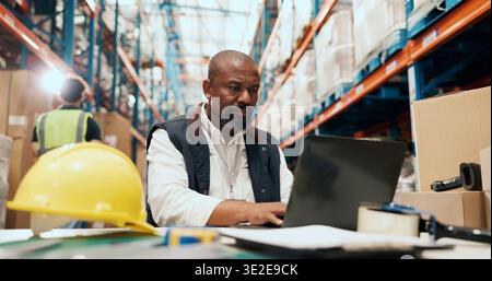 Shipping, man and typing on laptop in warehouse for order tracking, export status or distribution. Logistics staff, mature manager or tech for stock Stock Photo