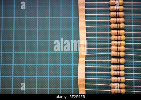 Row of resistors on carrier tape with copy space on cutting mat, electronic components background Stock Photo