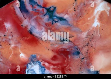 Abstract fluid art background with swirling pattern of vibrant red, coral, white, contrasting dark blue. Close up macro shot of epoxy resin, alcohol i Stock Photo