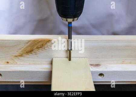 Close-up of drilling wooden board with power drill. Process of carpentry working at home Stock Photo