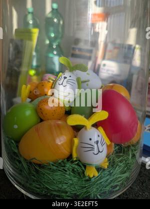 Bright Easter Eggs And Bunny Figurines Arranged In Glass Jar With Artificial Grass, Pastel Palette, Painted Details, Cozy Indoor Tabletop Vignette By Stock Photo