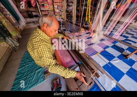 High-angle view of a weaver in Bundi meticulously operating a handloom to produce traditional fabrics in his small workshop. Stock Photo