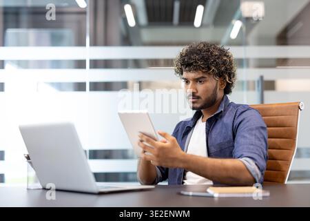 Muslim young man is working in the office with a laptop and using a tablet. Stock Photo
