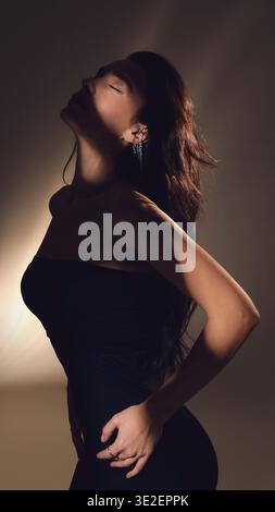 Side profile of woman with closed eyes and long hair in soft shadow light. Stock Photo
