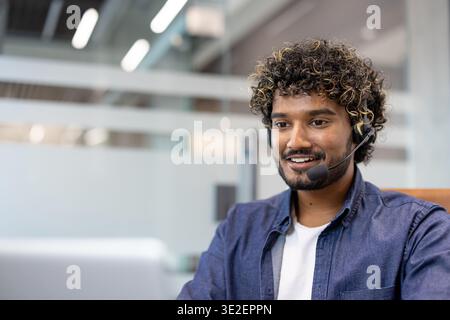 Close-up photo of an Indian man in a suit and headset working and studying on a laptop. Stock Photo