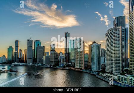 A vibrant Brisbane city skyline at sunset, reflecting on the river with tall glass buildings. Stock Photo