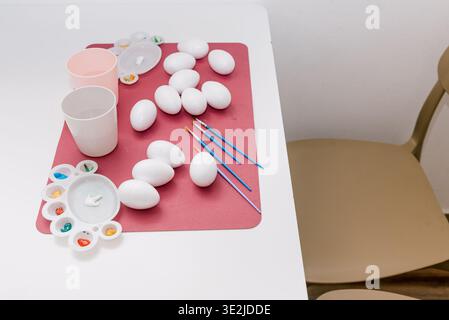 White plastic eggs and color paints on flat lay, traditional leisure festive Easter creativity drawing DIY Stock Photo