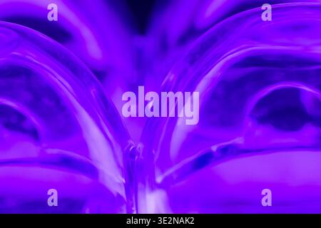 An abstract composition of an upside down plastic egg carton reflecting purple light from below. Stock Photo