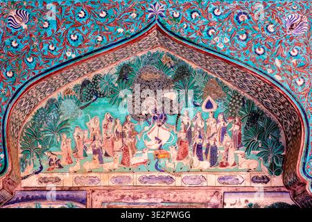 A detailed mural in the Chitrashala of Bundi depicts Lord Krishna dancing with gopis surrounded by peacocks within an ornate arch. Bundi Rajasthan Ind Stock Photo