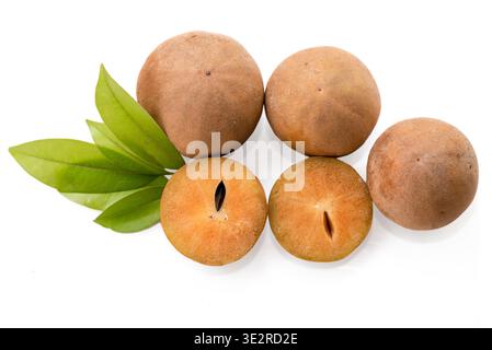 Fresh sapodilla (chikoo) fruit cut in half with green leaves isolated on background Stock Photo