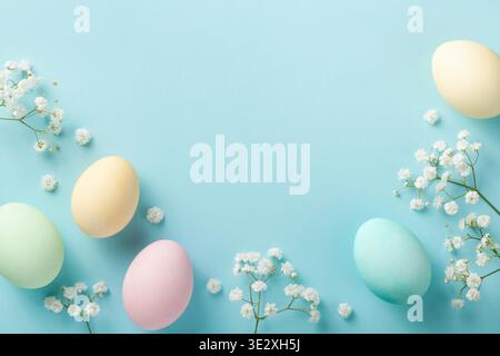Pastel Easter eggs on blue background top view. Flat lay style. Stock Photo