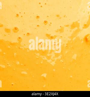 Abstract background showing bright yellow orange liquid with tiny bubbles and splatters Stock Photo