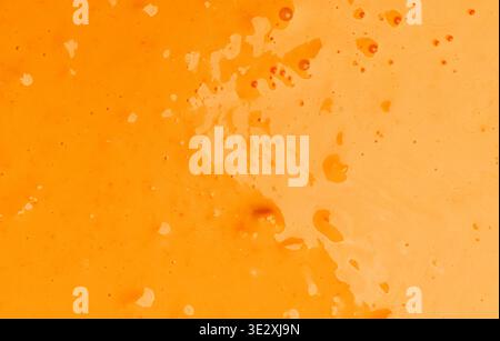 Orange liquid paint splashing on a surface creating a vibrant texture Stock Photo