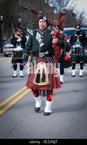 A bagpiper from the Amerscot Highlands Pipe Band marches & plays at the 2026 St Patrick's Day Parade in Beacon, New York. Stock Photo