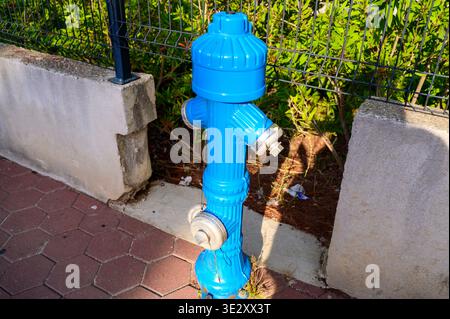 Close up of a bright blue iron fire plug near a residential area. Concept of neighborhood safety routine, reliable public utility, and modern urban in Stock Photo