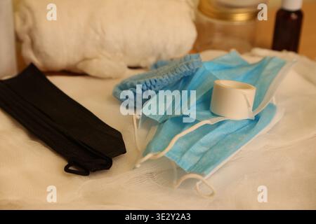 Different medical supplies are placed on a table. There are masks, elastic bands, tape, and cotton materials used for health care. This scene shows preparation for health-related tasks. Stock Photo