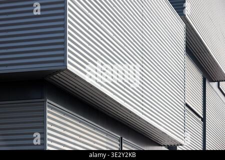 Architectural facade with gray cladding corrugated metal panels of industrial or commercial building, contemporary architecture with vertical relief a Stock Photo