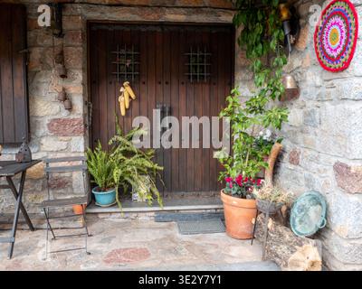 A charming, traditional rustic entrance featuring a large, dark wooden double door set into a rough stone facade. The scene is decorated with various Stock Photo